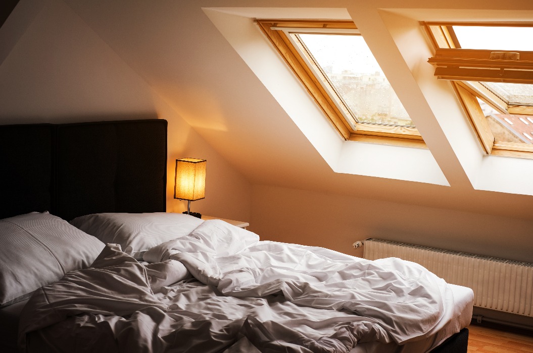 Schlafzimmer im skandinavischen Stil mit weißem Bett und Oberlichtern