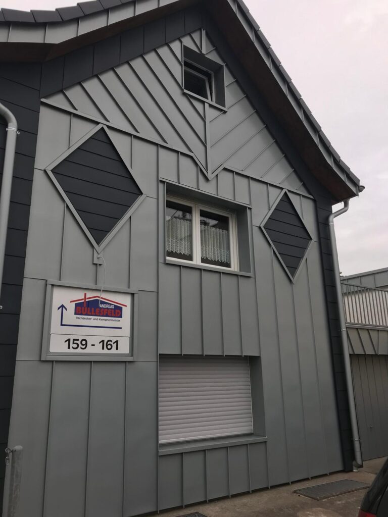 Modernes Gebäude mit grauen Platten, künstlerische Rautenformen an der Fassade.