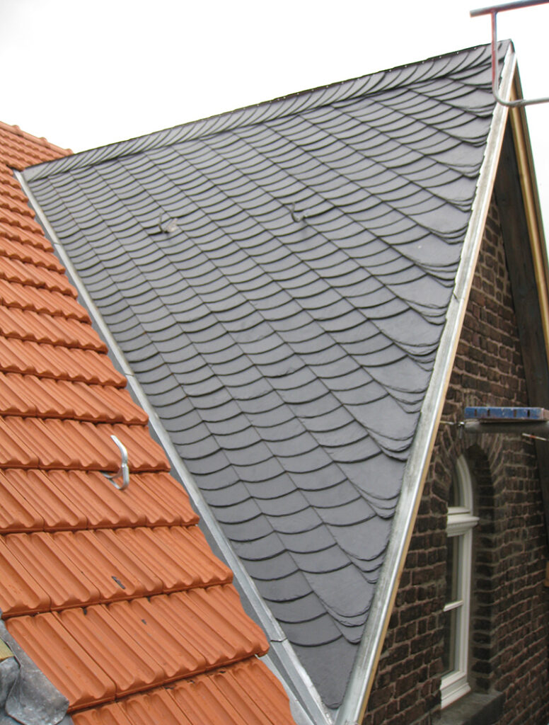 Dach mit roten Ziegeln und grauen Schieferplatten, die ein innovatives Design zeigen.
