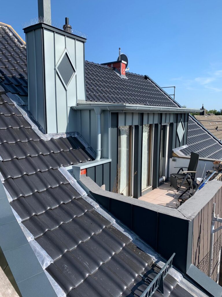 Dachterrasse mit modernen grauen Dachziegeln und Sonnenschirmen, unter blauem Himmel.